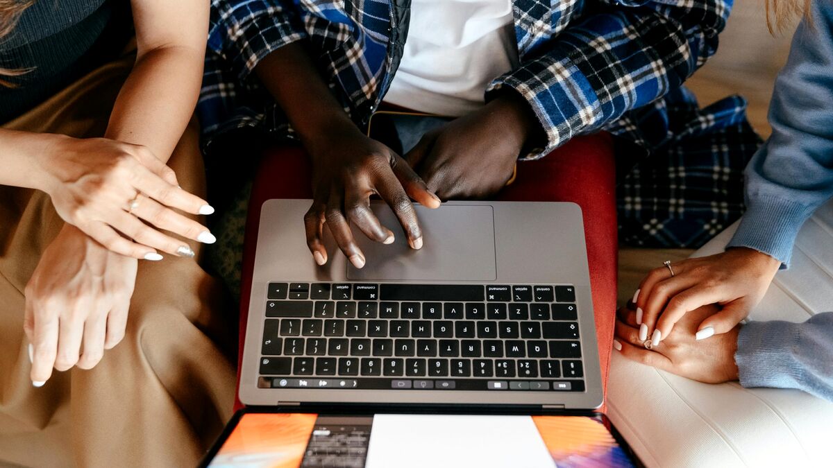 Three people sitting together looking at a laptop, going through a website audit