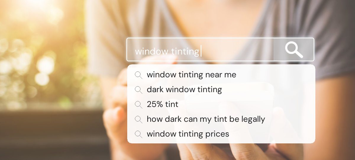 Hand holding a phone under a search bar reading window tinting, with five related search suggestions below it